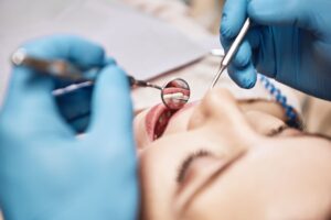 Closeup of woman undergoing dental exam by hands in blue gloves